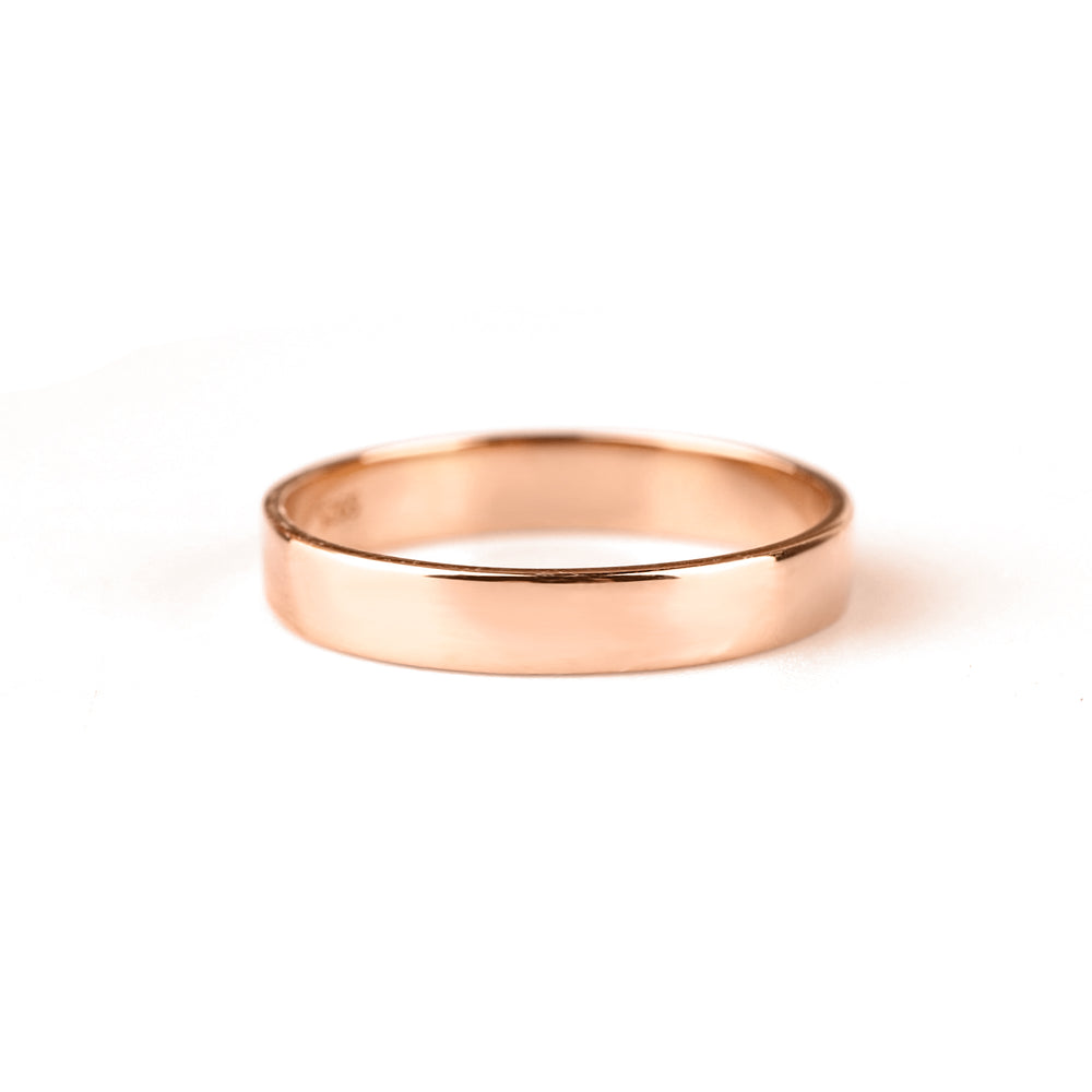 A gold-colored metal band ring with a smooth, flat surface against a white background.