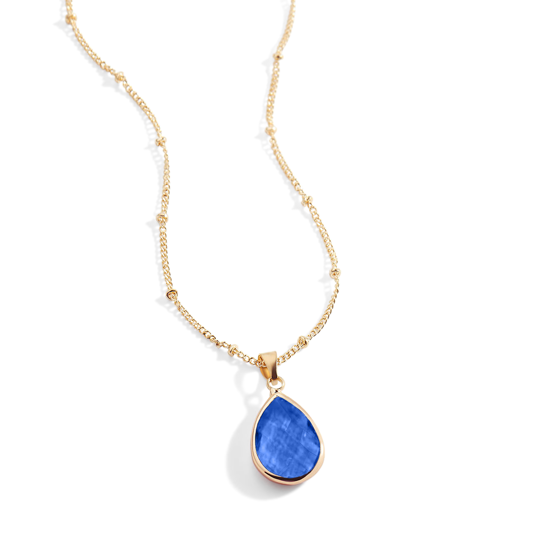 Gold necklace with a blue teardrop pendant on a white background