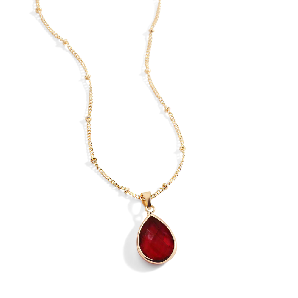 Gold necklace with a red teardrop pendant on a white background