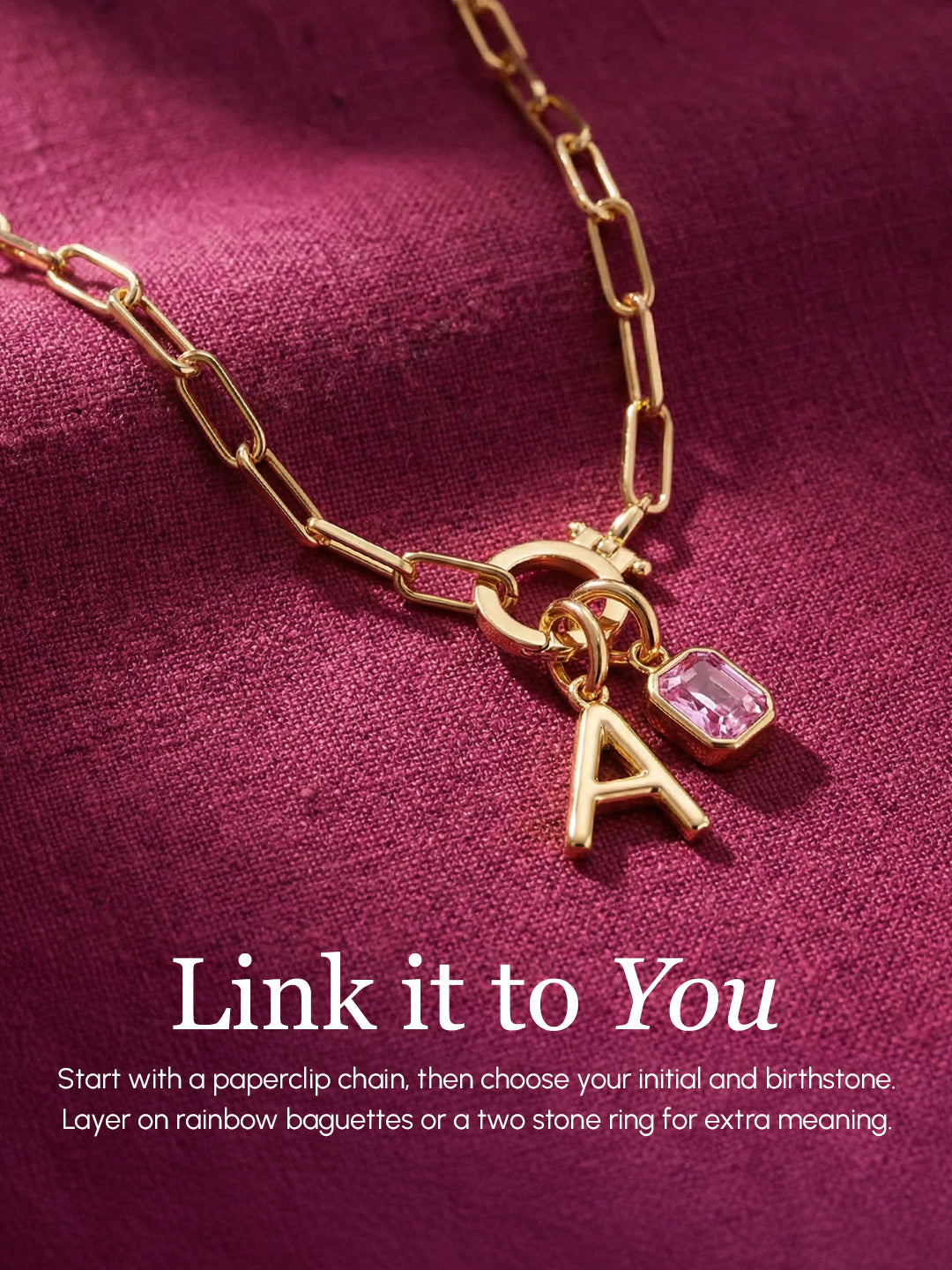 Gold necklace with letter 'A' charm and pink gemstone on a purple background
