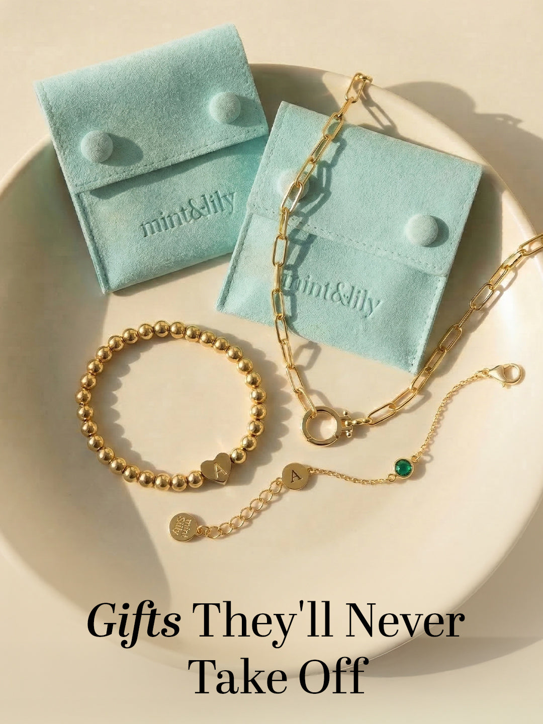 Gold jewelry including bracelet, necklace, and charm pieces displayed with gift boxes and ‘Gifts They’ll Never Take Off’ text.