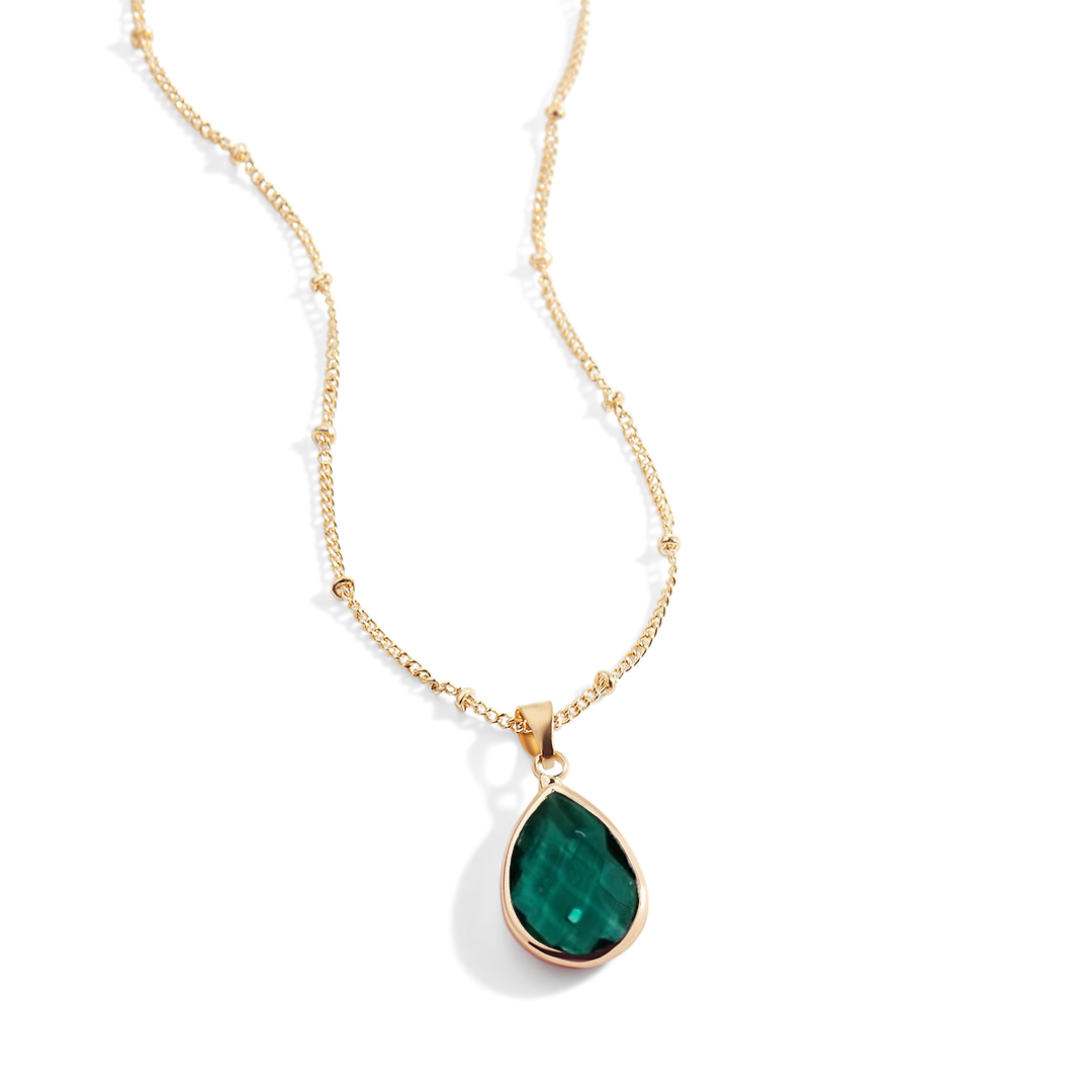 Gold necklace with a green teardrop pendant on a white background