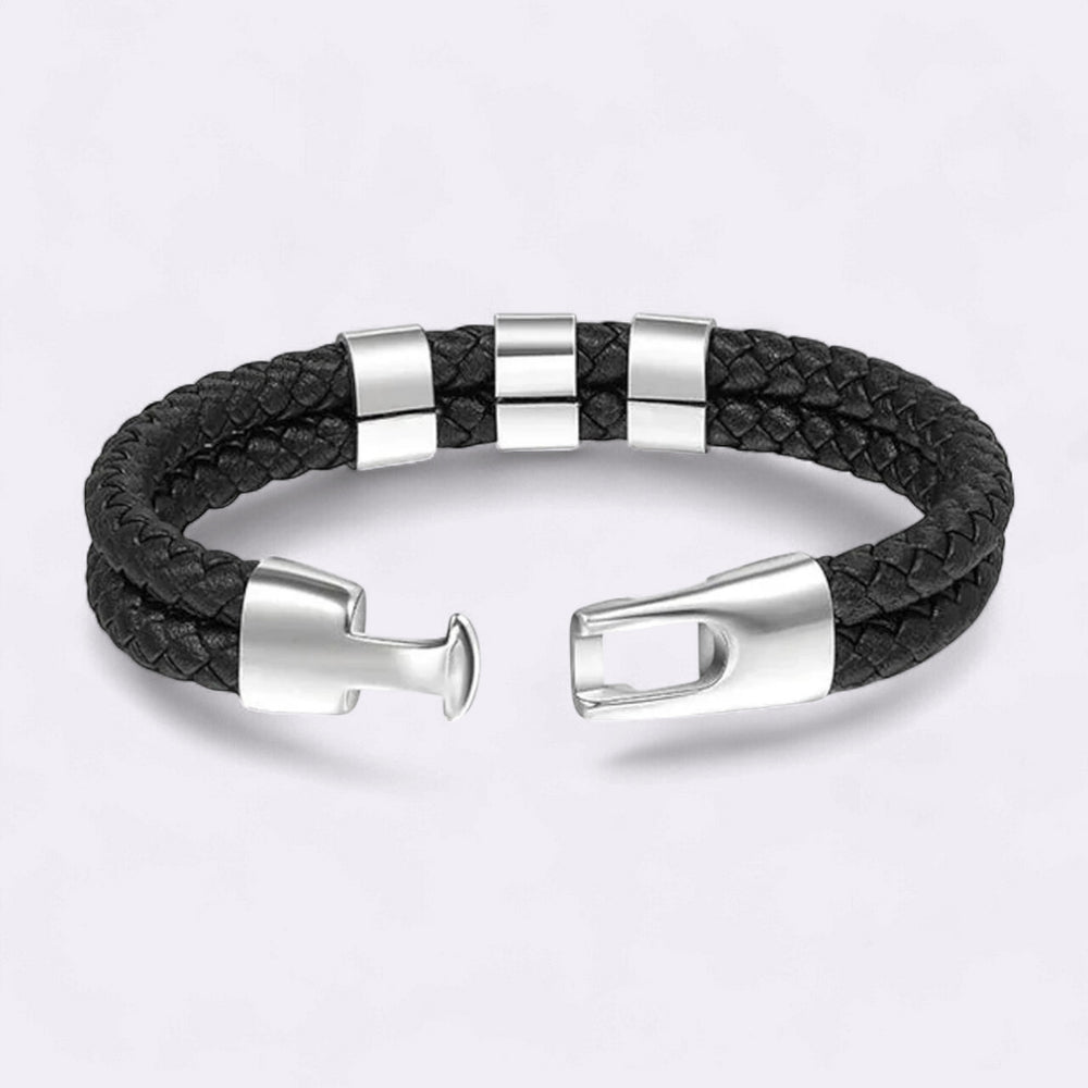 Black braided leather bracelet with silver metal clasps on a light gray background