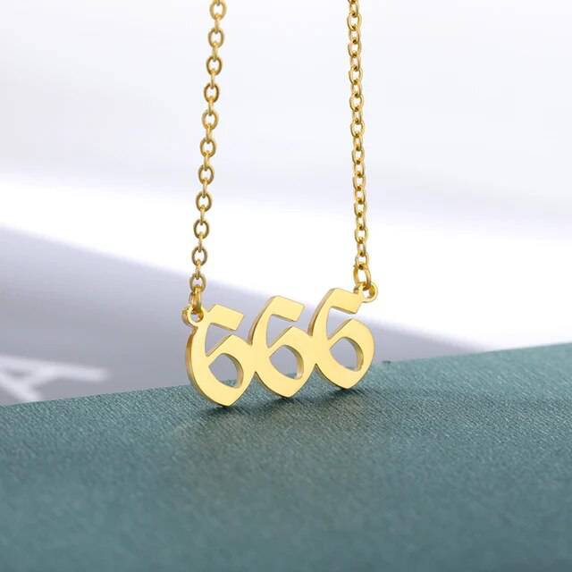 A gold-colored necklace with the angel number 444 pendant on a chain.