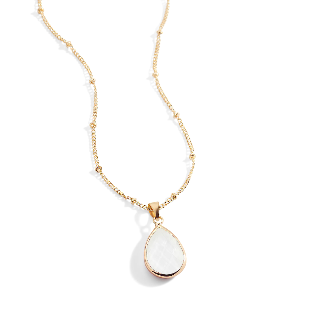 Gold necklace with a white teardrop pendant on a light gray background