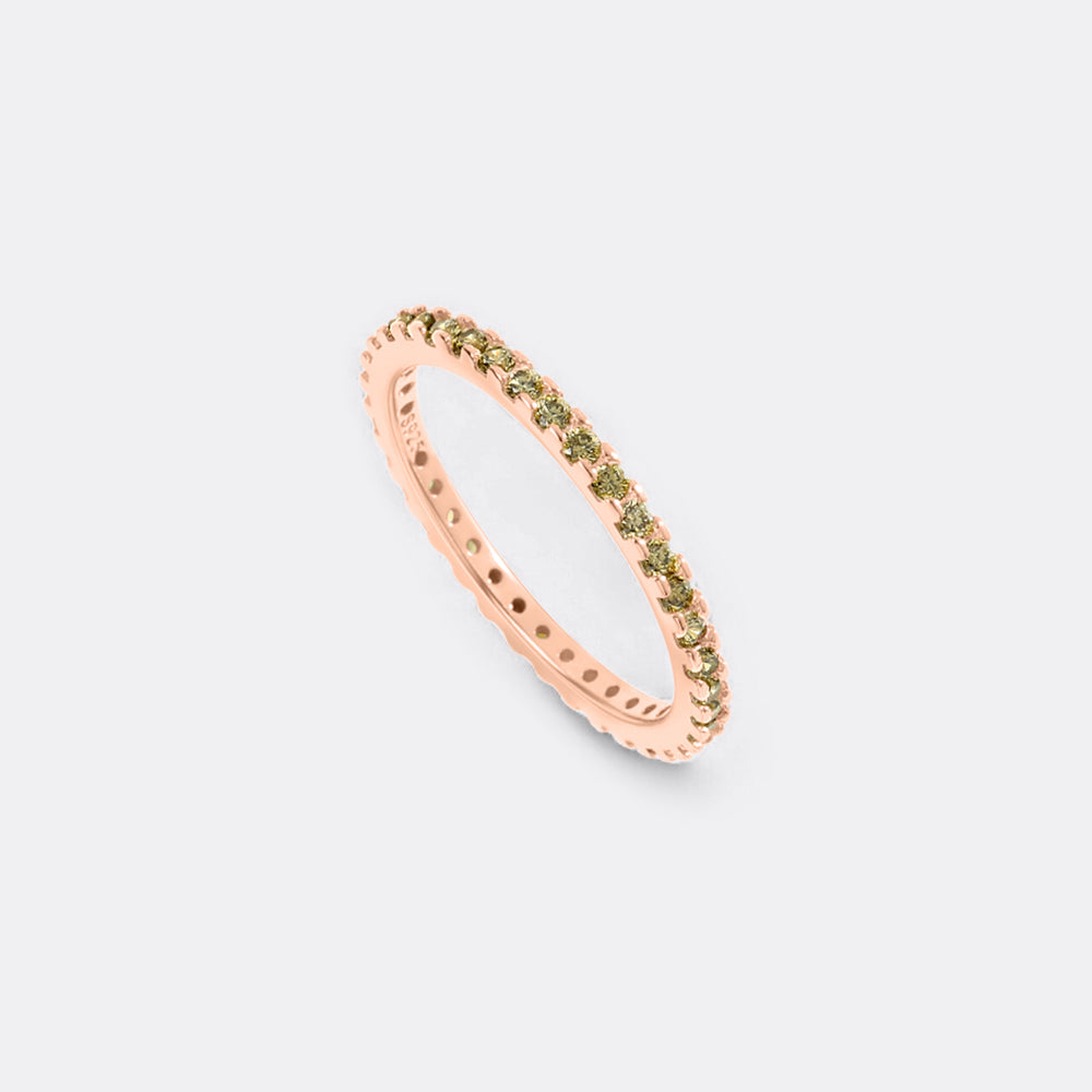 Rose gold ring with green gemstones on a light gray background