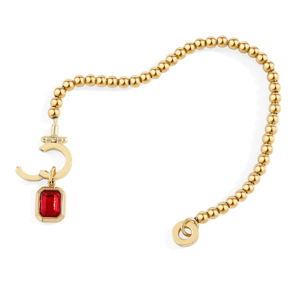 Gold bracelet with red gemstone charm on a white background
