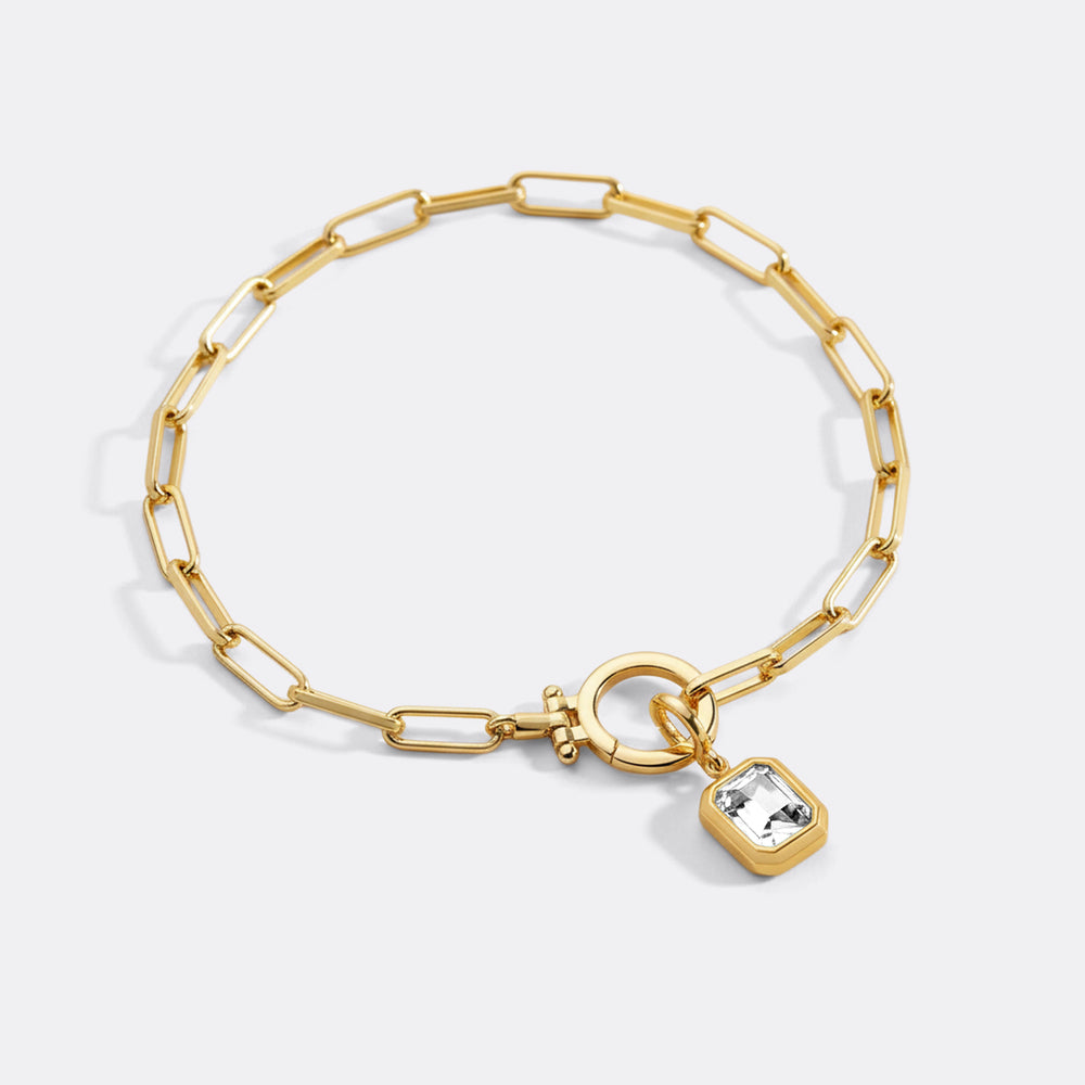 Gold bracelet with a heart-shaped charm on a white background