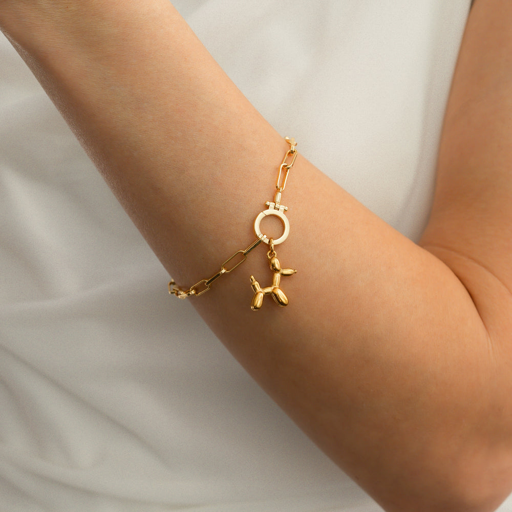 Gold bracelet with a unique charm on a wrist against a neutral background