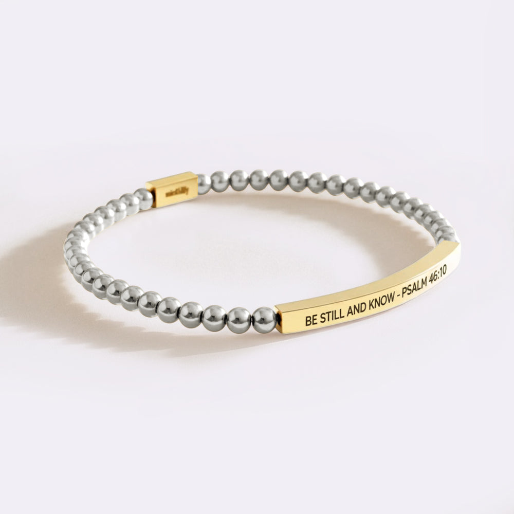 Bracelet with gray beads and gold tag on a white background
