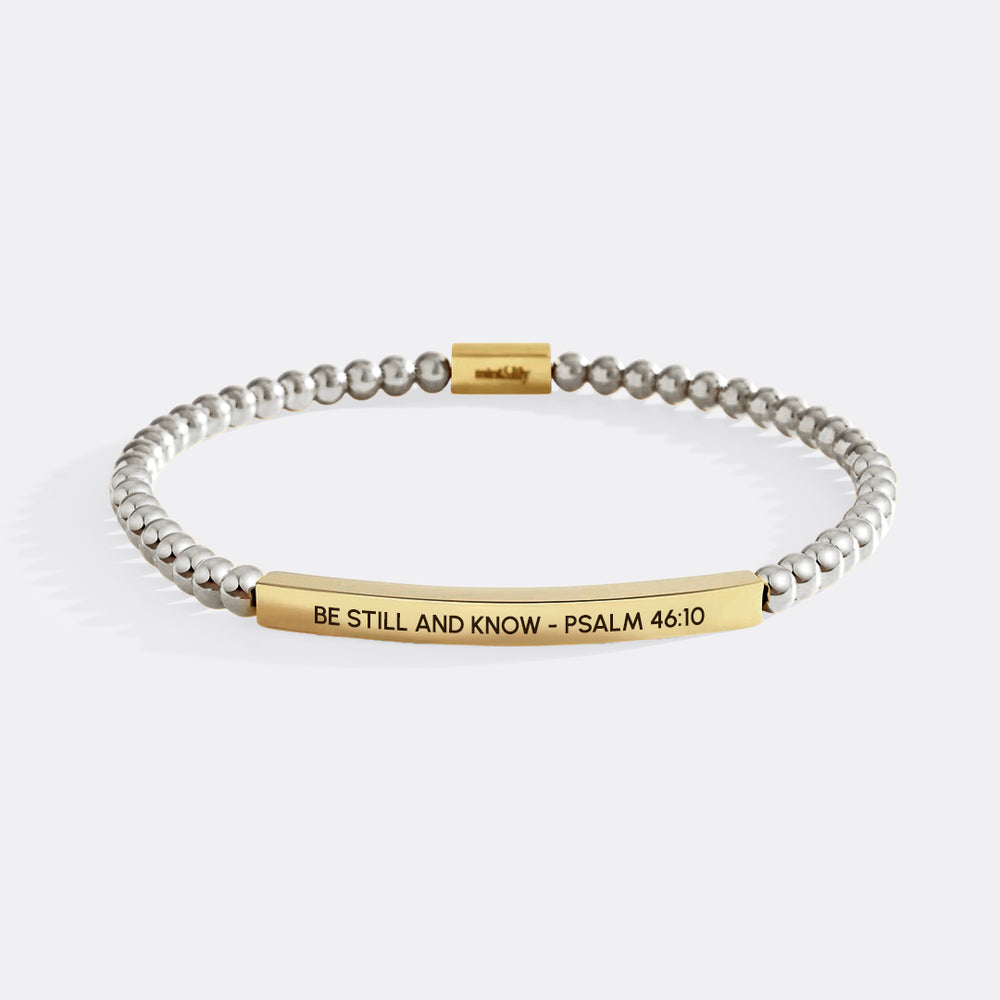 Bracelet with gold and silver beads and engraved text on a white background