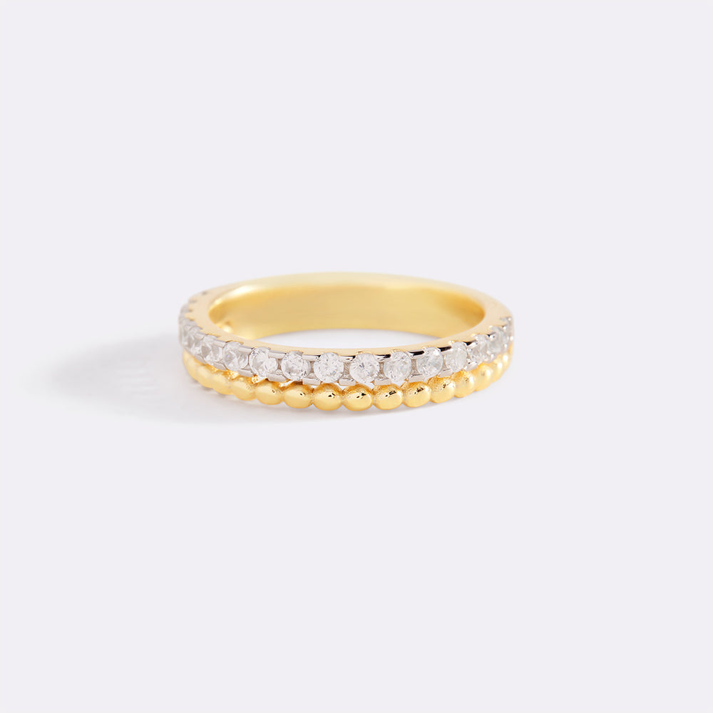 Gold ring with embedded diamonds on a light gray background