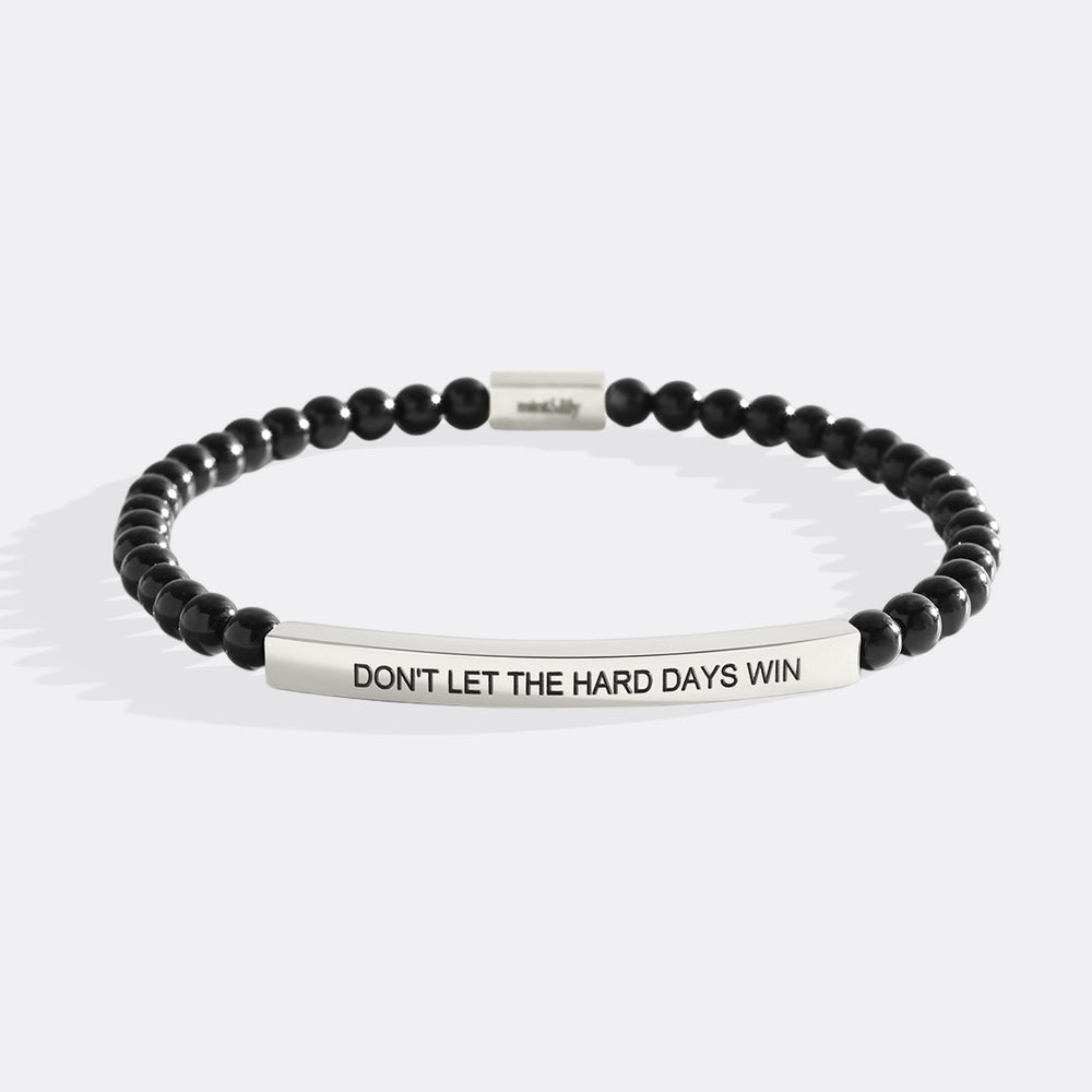 Black beaded bracelet with silver bar and motivational message on a white background