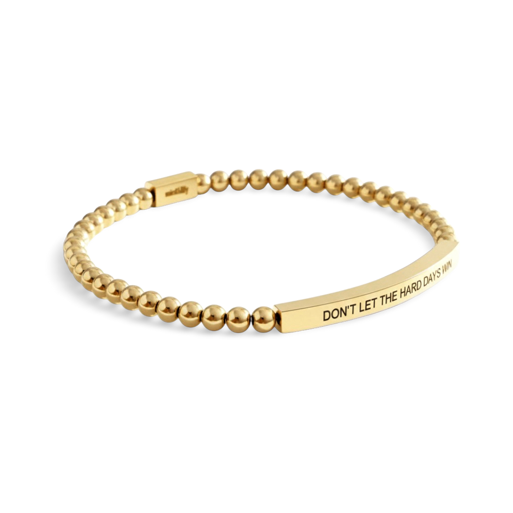 Gold beaded bracelet with engraved message on a white background