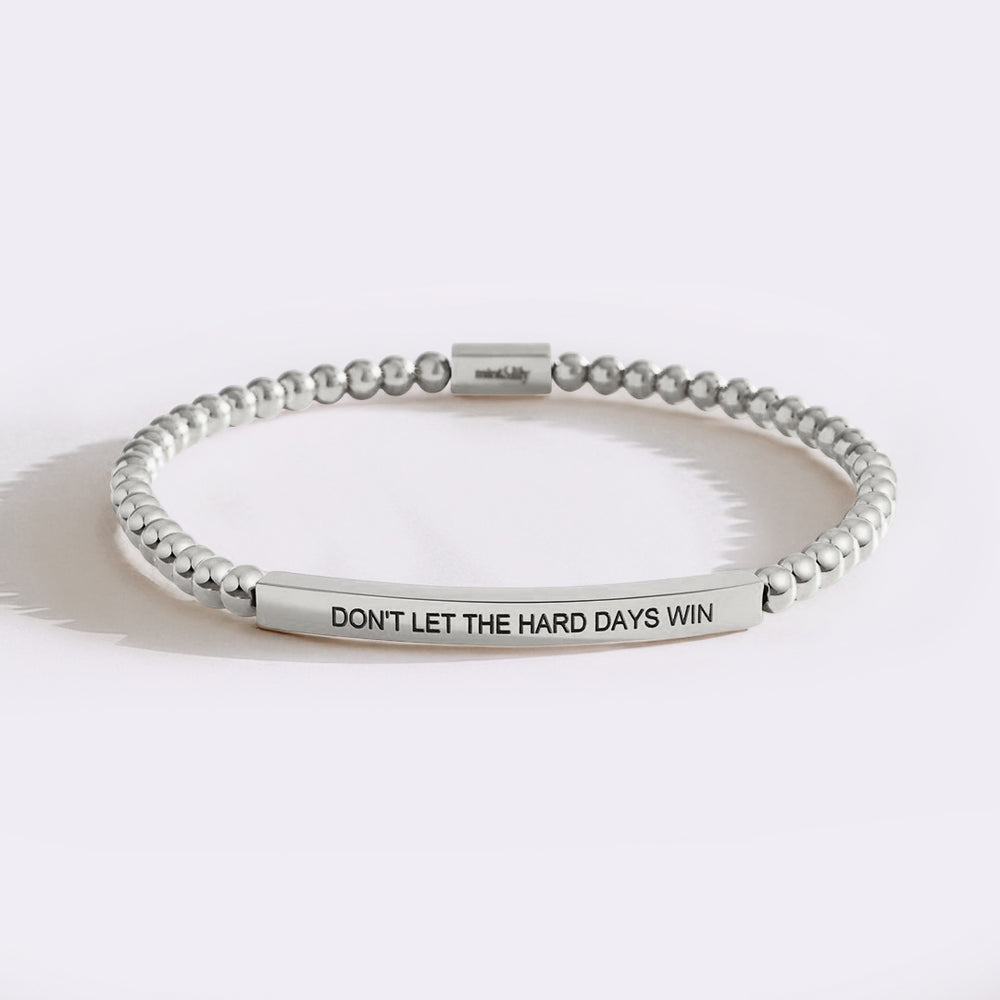Silver beaded bracelet with motivational message on a white background