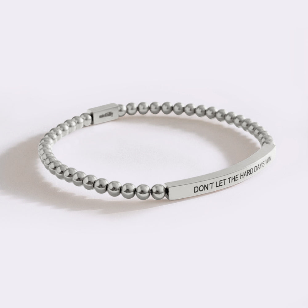Silver beaded bracelet with engraved message on a white background