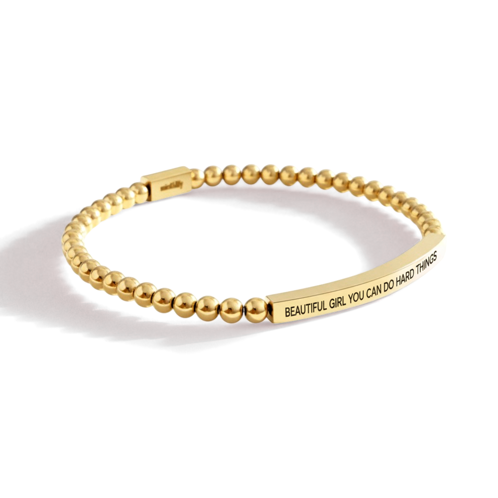 Gold beaded bracelet with motivational message on a white background