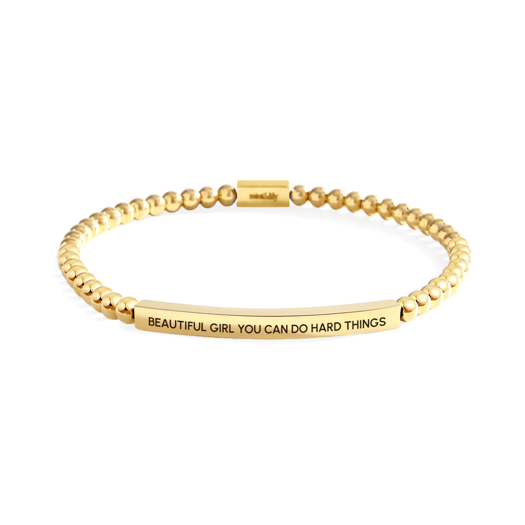 Gold bracelet with motivational message on a white background