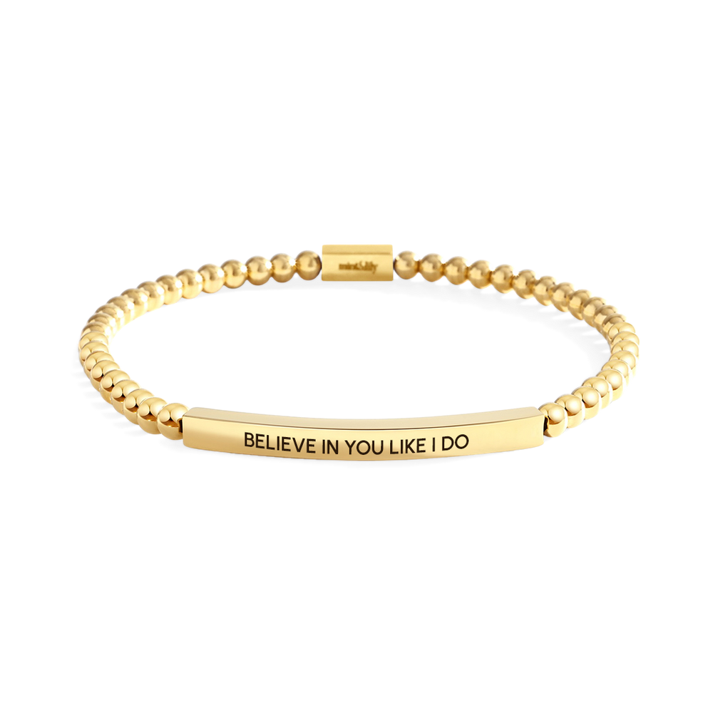 Gold bracelet with engraved message on a white background