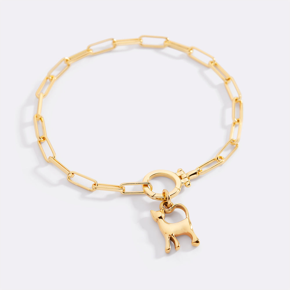 Gold bracelet with a dog charm on a light gray background