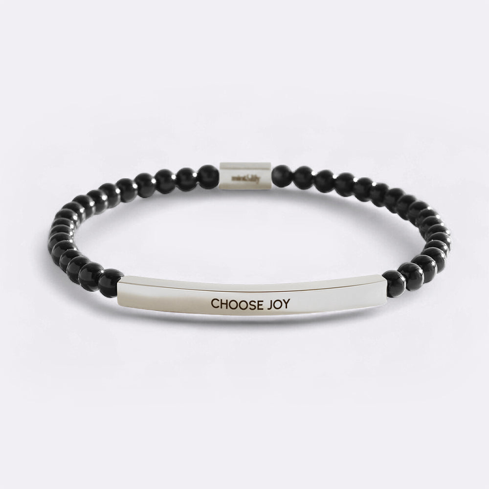 Black beaded bracelet with a silver bar featuring 'CHOOSE JOY' on a light gray background