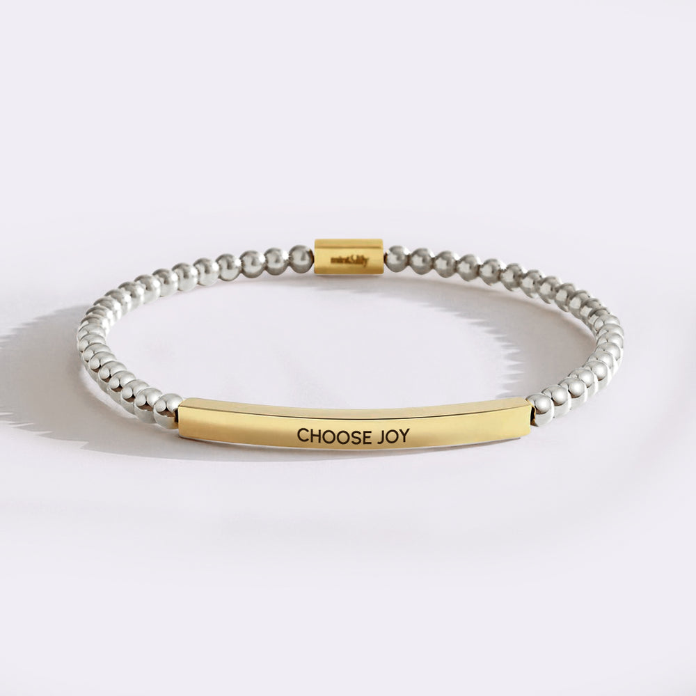 Bracelet with gold bar and 'CHOOSE JOY' engraving on a white background