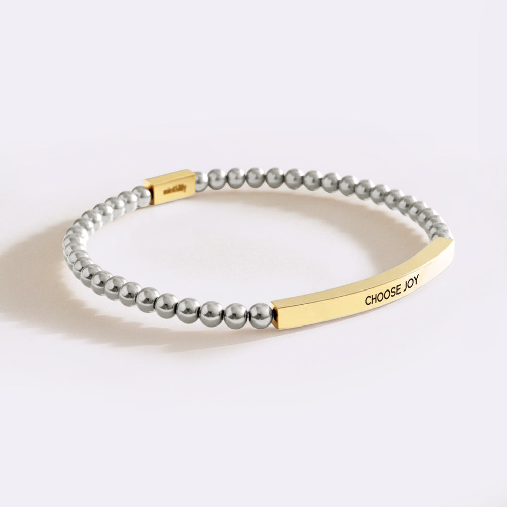 Bracelet with gray beads and gold tag on a white background