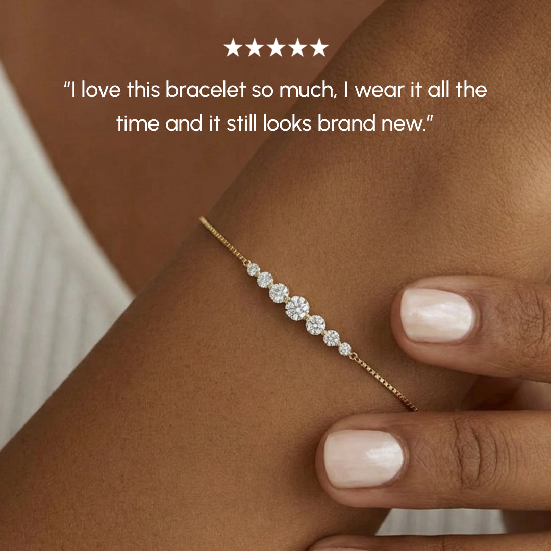 Gold bracelet with diamonds on a wrist, worn by a person with a neutral background.