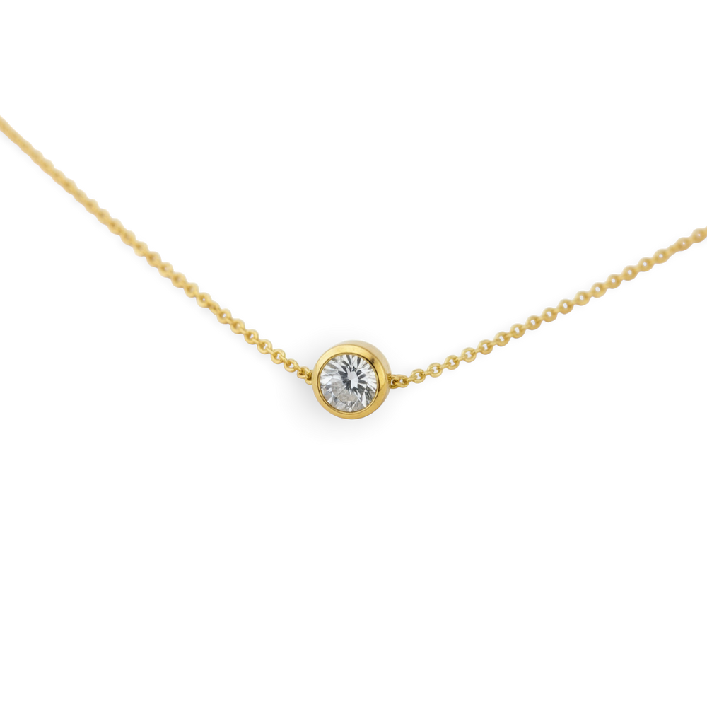 Gold necklace with a single diamond pendant on a light gray background