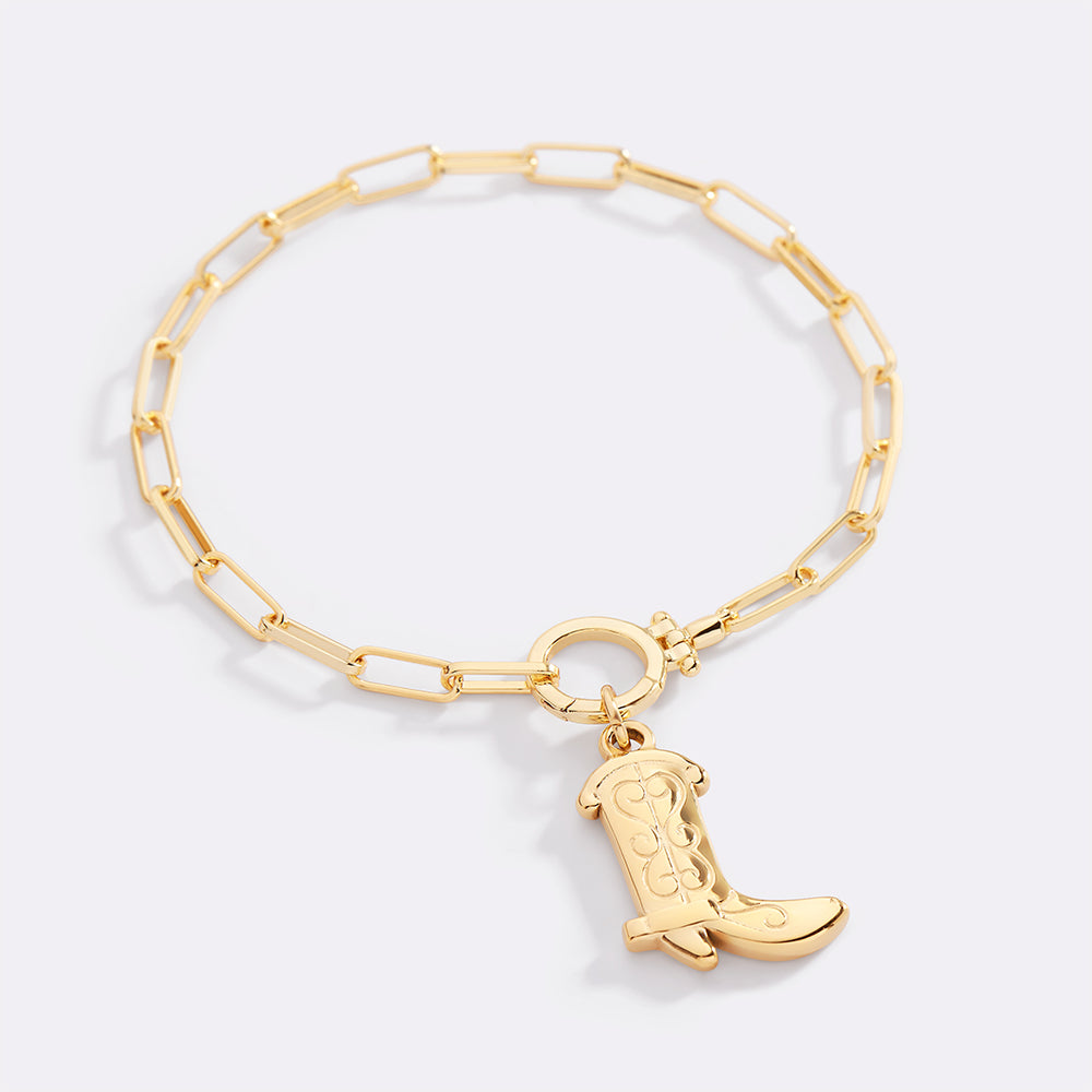 Gold bracelet with a cowboy boot charm on a light gray background