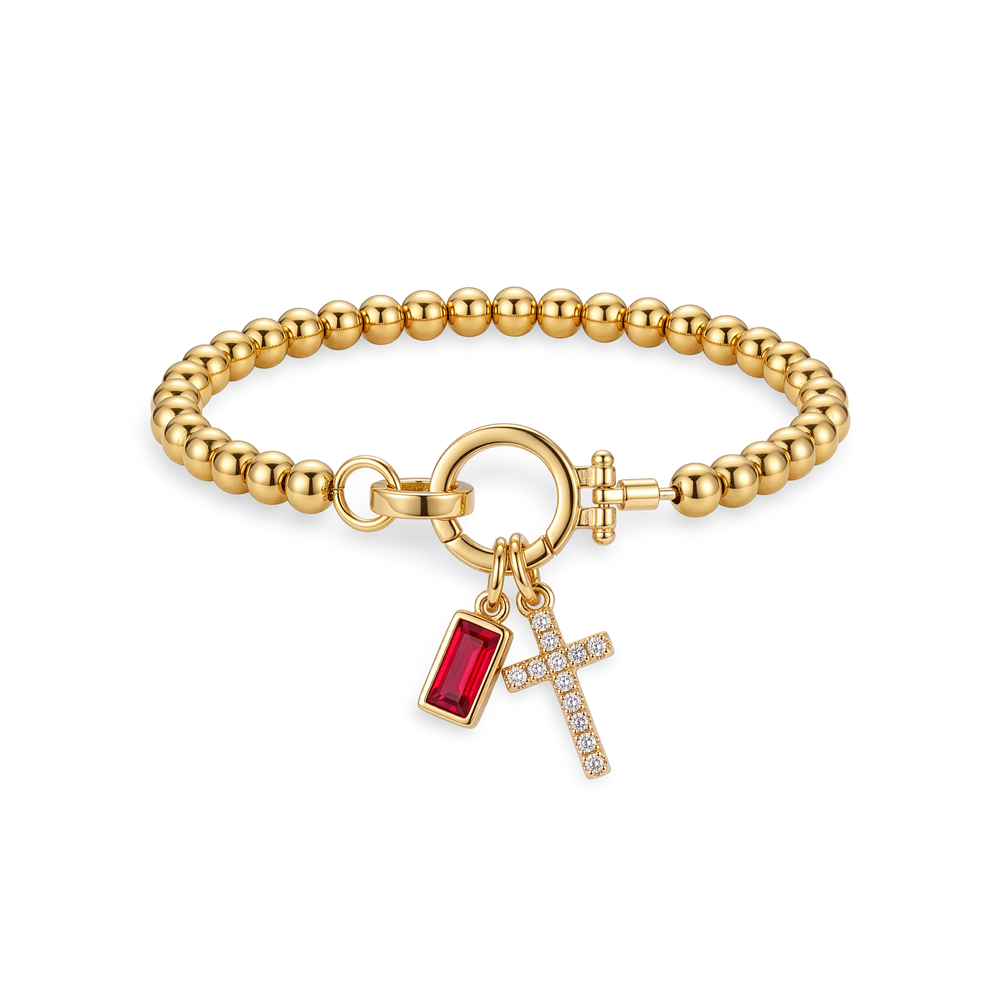 Flat lay of the Cross Charm Birthstone Bracelet with January garnet birthstone charm.