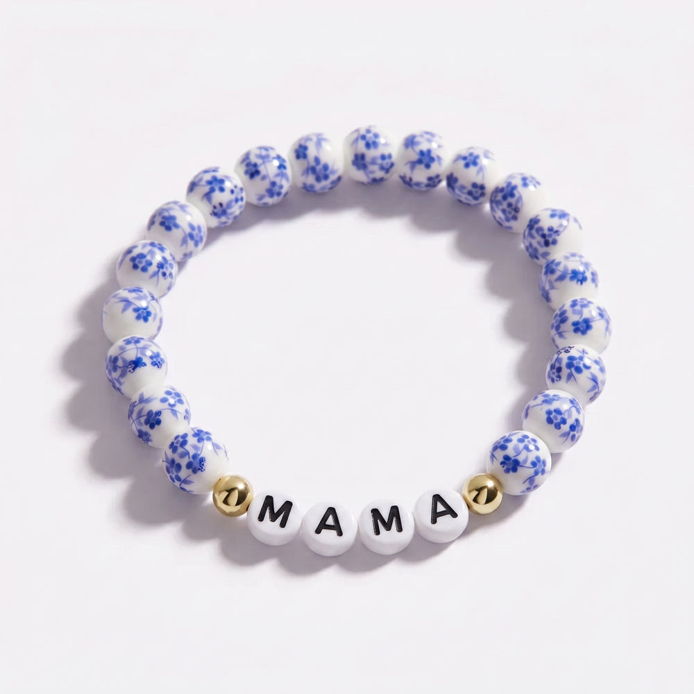 Blue and white floral beaded bracelet with 'MAMA' charm on a white background