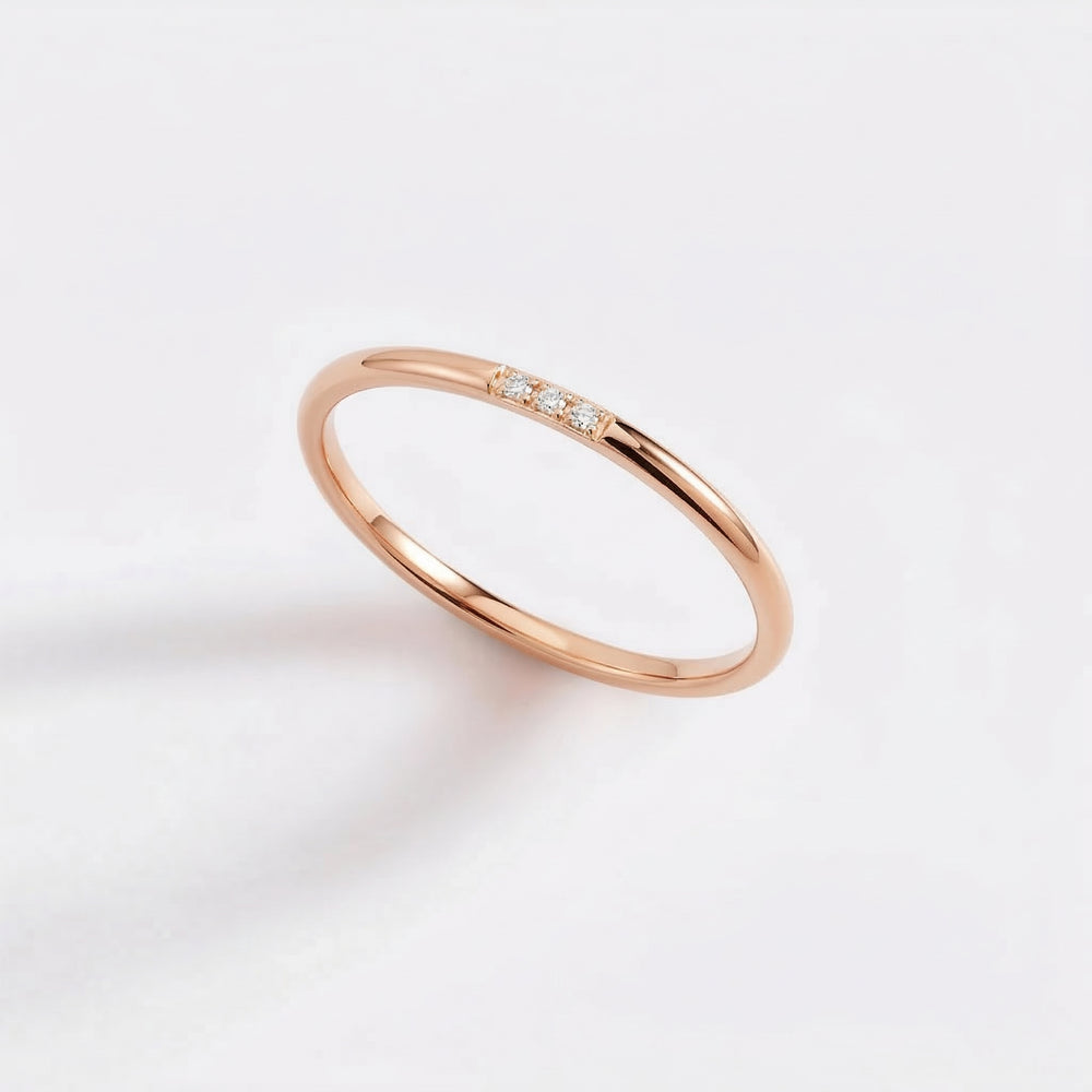 Rose gold ring with small diamonds on a light pink background