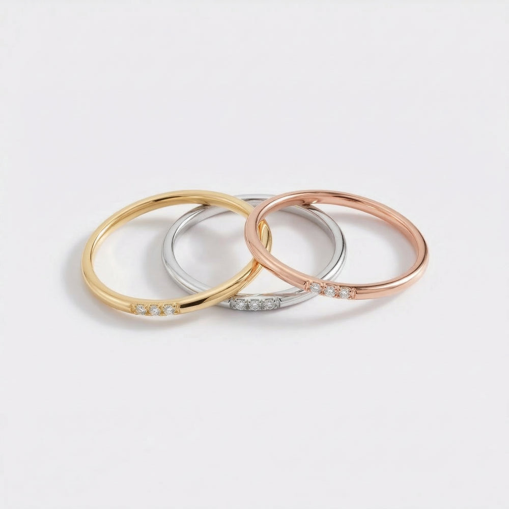 Three gold, silver, and rose gold bangles on a light gray background