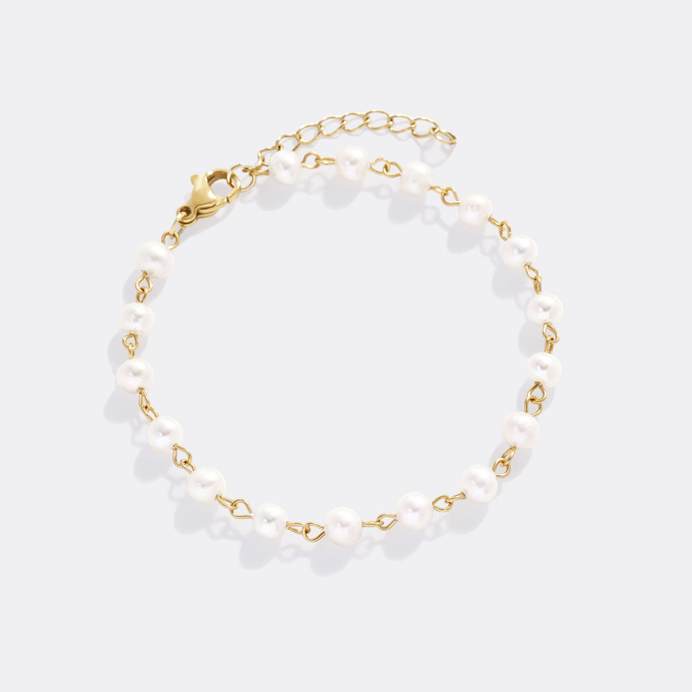 Bracelet with white beads and gold chain on a light gray background