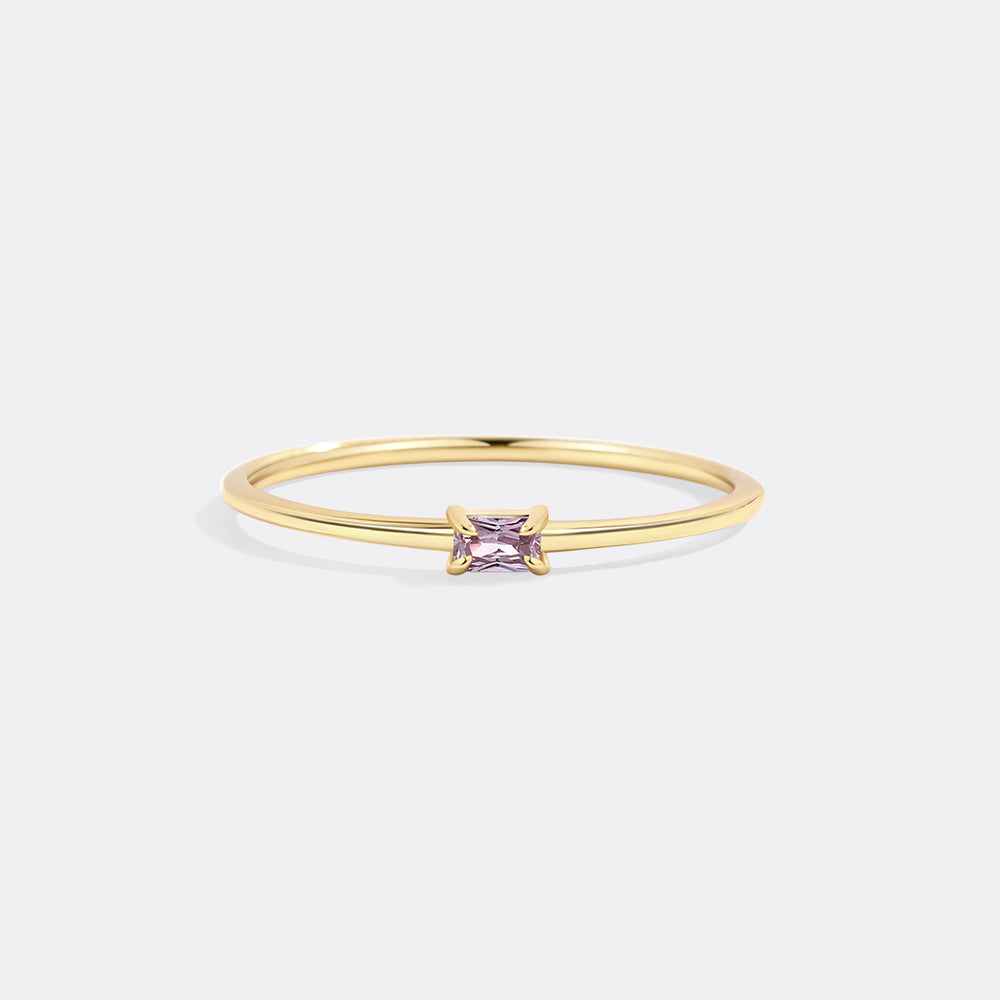 Gold ring with a purple gemstone on a white background