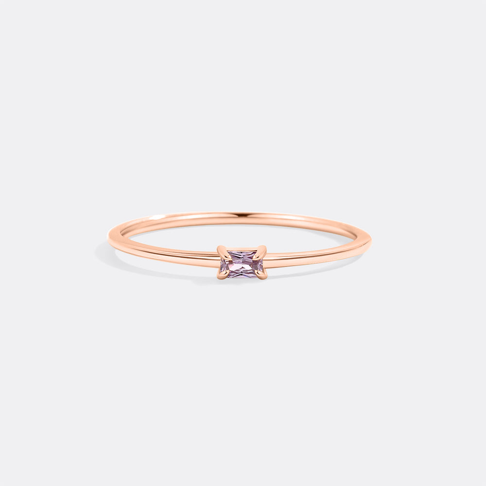 Rose gold ring with a square purple gemstone on a light gray background
