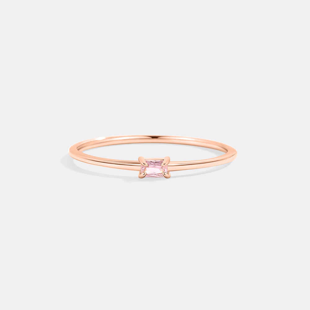 Rose gold ring with a pink gemstone on a light gray background