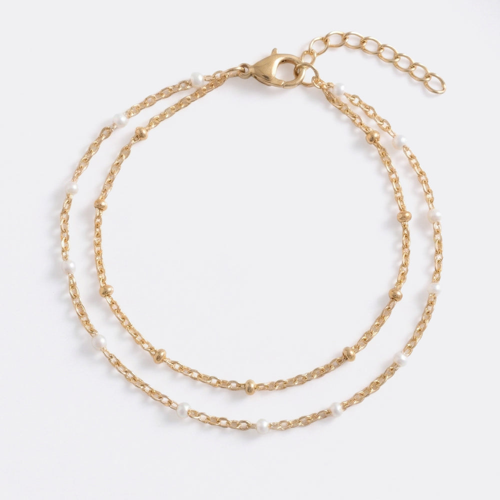 An elegant double chain bracelet accented with fine white accents designed for a refined, understated glow. Perfect for effortless everyday luxury.