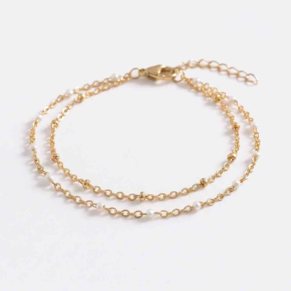 An elegant double chain bracelet accented with fine white accents designed for a refined, understated glow. Perfect for effortless everyday luxury.