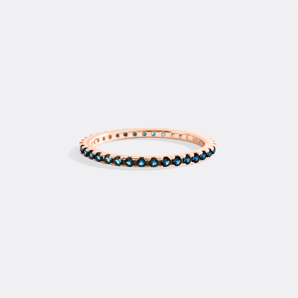Rose gold ring with blue gemstones on a light gray background