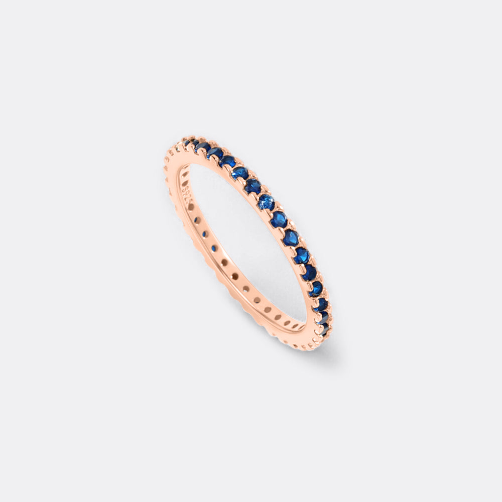 Rose gold ring with blue gemstones on a light gray background