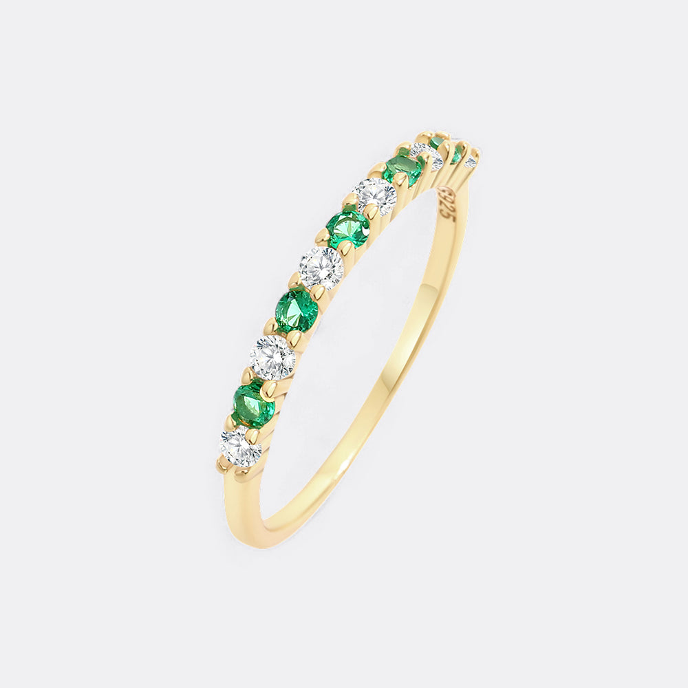 Gold ring with green gemstones on a white background