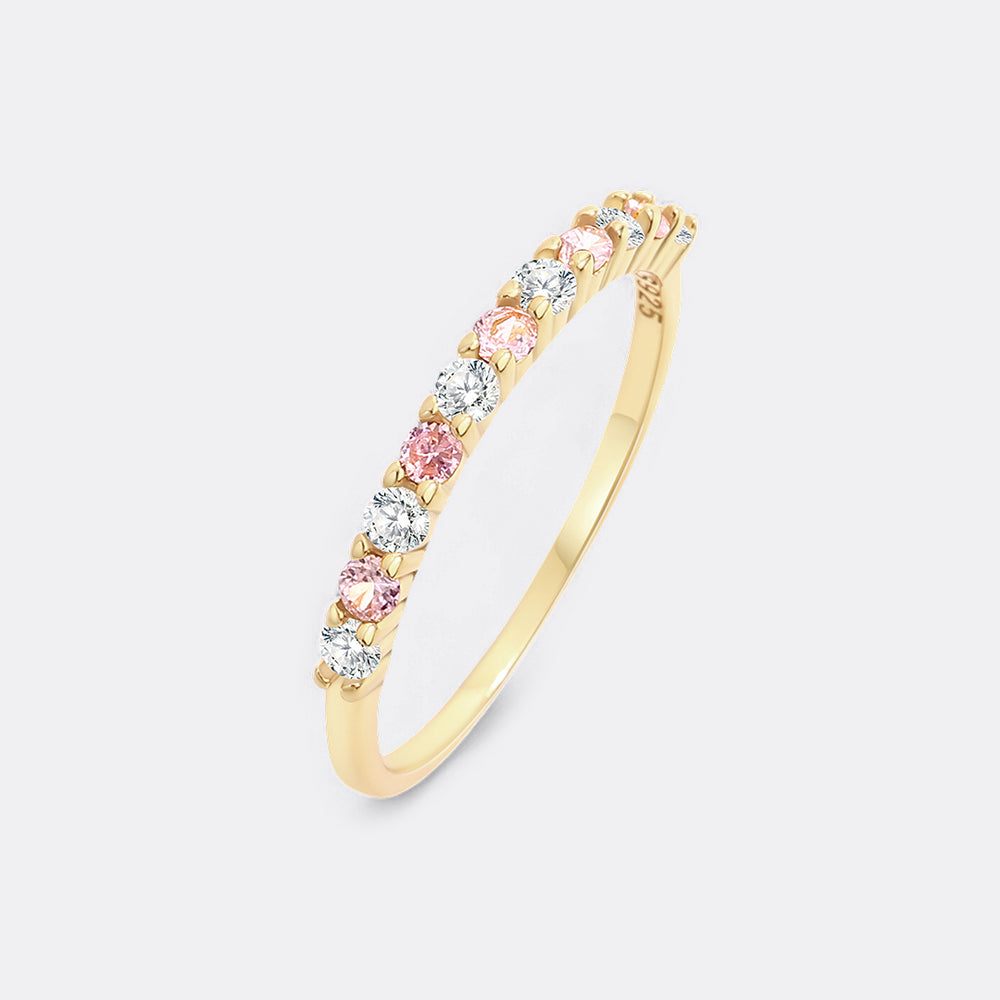 Gold ring with pink and clear gemstones on a white background