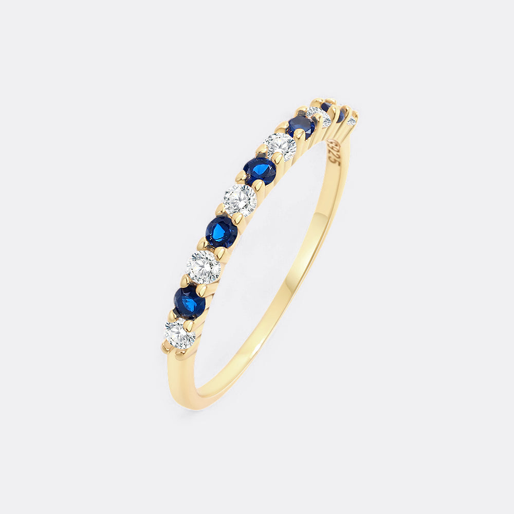 Gold ring with blue and clear gemstones on a white background