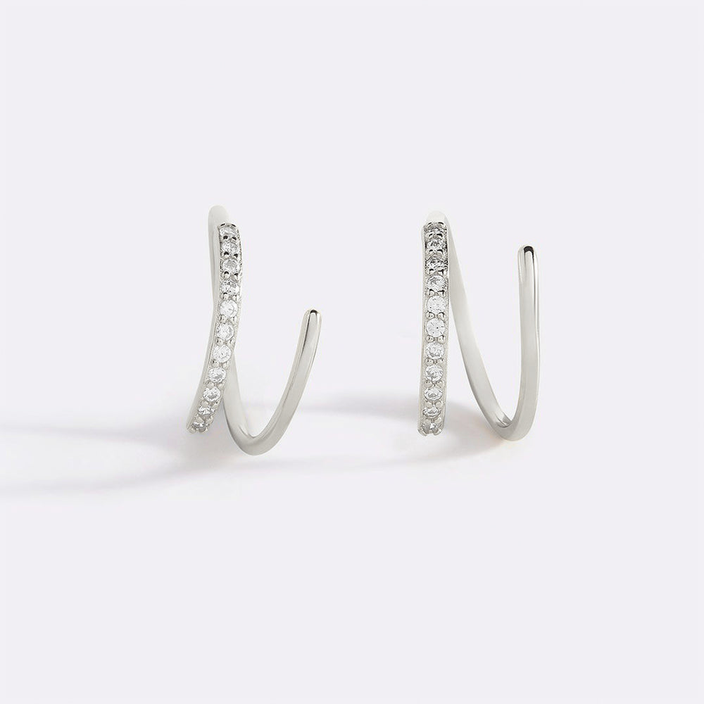 A pair of huggie hoop earrings with gold plating and embedded with 5A cubic zirconia stones on the loops.
