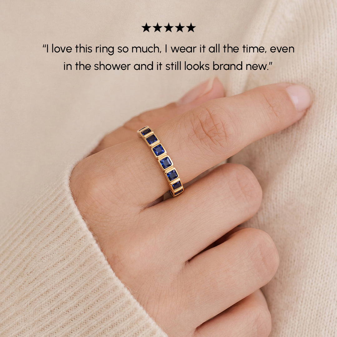 Gold ring with blue stones on a finger, with a five-star rating and customer review text.