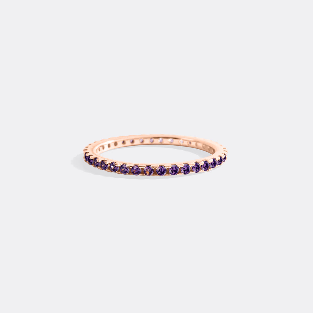Rose gold ring with purple gemstones on a light gray background