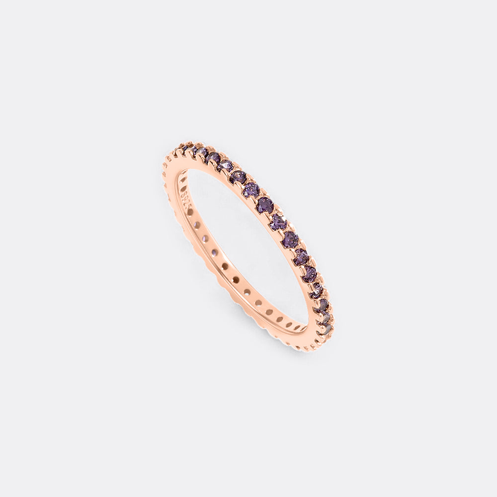 Rose gold ring with purple gemstones on a light pink background