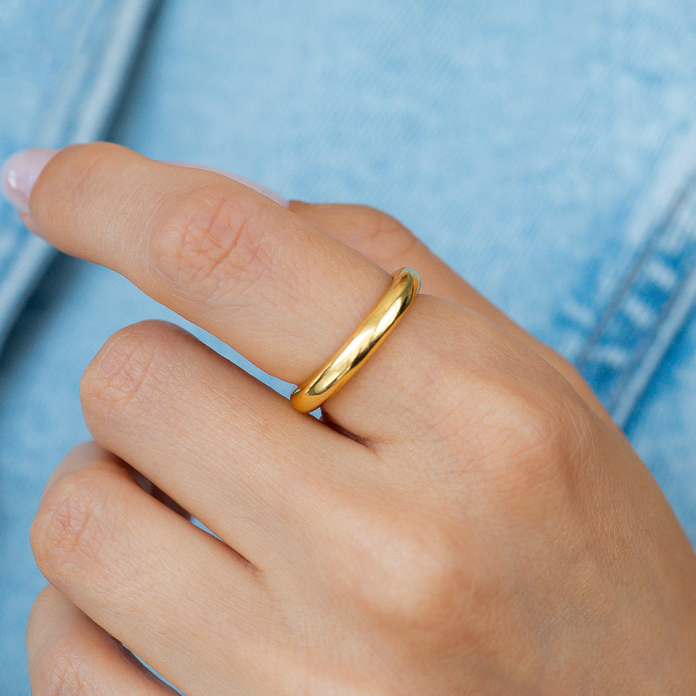 Gold ring on a person's finger against a blue denim background